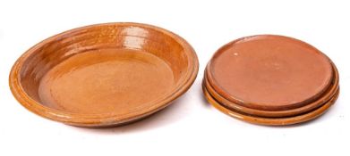 A terracotta and brown slip glazed circular shallow dairy bowl:, 50cm diameter,