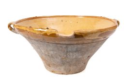 A terracotta, yellow and ochre slip glazed single lipped circular dairy bowl:, 48cm diameter.