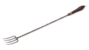 A metal four pronged toasting fork:, the handle with shaped shaft and turned wood baluster terminal,