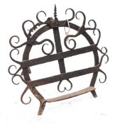 An Irish wrought iron bread iron or harnen stand: of horseshoe outline with hooked scroll designs,