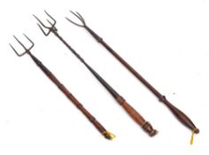 An iron four pronged flesh fork: with turned wood handle and two iron three pronged flesh forks
