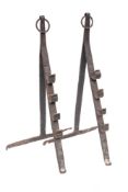 A pair of wrought iron spit dogs: of easel type with ring finials, with hook for four heights,