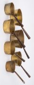 Seven brass saucepans: of graduated size with iron cone handles.