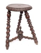 A 19th Century turned beechwood milking stool:, the circular seat with lunette foliate carved edge,