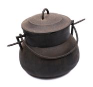 A large iron twin-handled cooking cauldron and cover: with iron swing handle, 44cm across.