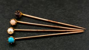 Four gemset stick pins,: respectively set with a cabochon-cut 'angel hair' coral, a seed pearl,