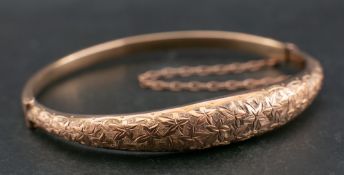 An Edwardian, 9ct gold, hinged bangle of bombe form, with engraved foliate decoration,