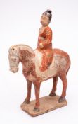 A Chinese funerary equestrian group: modelled with a rider in red robes seated on a white cloth