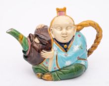 A Minton majolica 'Chinaman' teapot and cover: modelled seated in robes holding a large theatrical