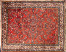 A Sarouk carpet:, the brick red field with all over designs of floral foliate sprays,