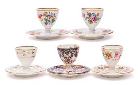 A group of five Derby egg cups on integral stands: including a Bloor 'Imari' cup,