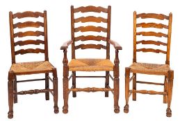 A composed set of twelve oak and rush seated ladder back dining chairs,
