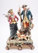 A large Continental porcelain figure group: modelled as a huntsman stood before a pillar and urn