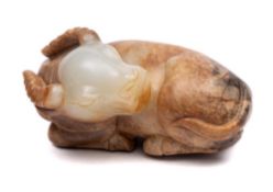 A Chinese jade carving of a water buffalo: the stone of mottled celadon, russet and grey colour,