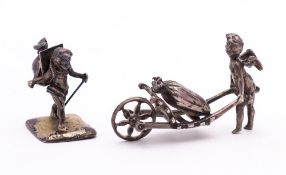 Two Continental white metal models of cherubs : one pushing a wheelbarrow,