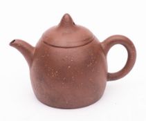 A small Yixing stoneware teapot and cover: the bullet shaped body of chocolate hue with sandy