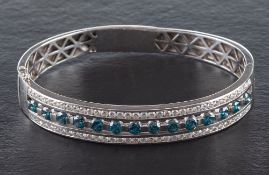 A hinged gold bangle with treated blue, round, brilliant-cut diamonds and white, round,