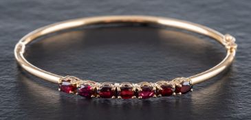 A 9ct gold bangle set with oval-shaped, mixed-cut garnets:, calculated total garnet weight ca. 2.