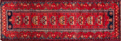 A Heriz runner:, the brick red field with a row of ten crown and flowering stem medallions,