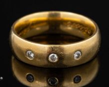An 18 carat gold and diamond ring,: the polished band set with three brilliant cut diamonds,