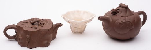 A Chinese Dehua blanc de Chine libation cup and two Yixing teapots and covers: the cup of