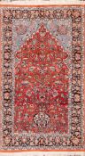 A Kashmiri silk prayer rug:, the brick red mihrab with a design of flowerheads,