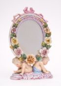 A Plaue en Havel porcelain mirror: of oval flower encrusted form with ribbon cresting supported on