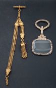 A late 19th century/ early 20th century gilt metal magnifying glass and watch chain,
