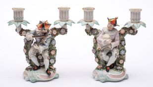 A pair of Sitzendorf porcelain two branch figural candelabra: each modelled as humorous musicians
