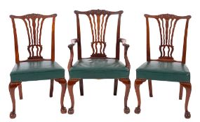 A set of seven mahogany and green leather upholstered dining chairs in George III style,