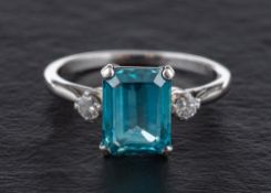A step-cut blue topaz and round, brilliant-cut diamond three stone ring,