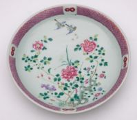 A Chinese famille rose charger: enamelled with two birds flying amongst peony branches issuing from