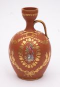 A terracotta ewer: of oviform with raised garlic neck and strap handle enamelled with an oval panel