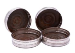 A set of four silver plated wine coasters: of circular outline,