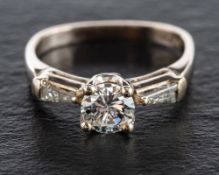 A round, brilliant and tapered baguette-cut diamond three stone ring,