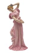 A large early Royal Doulton figure: of a girl dancer with elaborate ribbon and floral headdress,