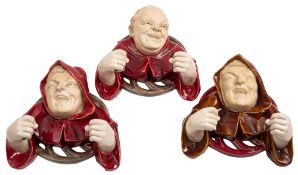 Three Austrian pottery wall appliques: in the form of jovial friars, one wearing a skull cap,