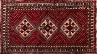 An Abadeh carpet:, the red field with triple ivory hooked medallions and all over geometric designs,