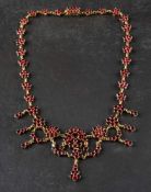 An early 20th century, silver gilt garnet necklace,: of flowerhead design with swagged pendants,