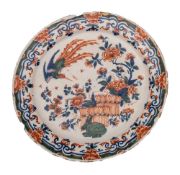 A Dutch polychrome delftware plate: painted in Kangxi style with an exotic bird in flight over a