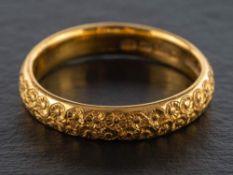 A 22ct gold band ring,: with chased floral decoration, hallmarks for Birmingham, 1927, ring size R,