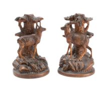 A pair of Black Forest candlesticks: modelled as stags standing below a tree,