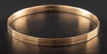 A 9ct gold bangle with engine-turned decoration,: with hallmarks for Birmingham, 1930,