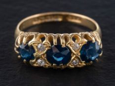 An 18ct gold sapphire three-stone ring with single-cut diamond accents,