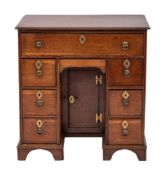 A George II oak kneehole desk, circa 1735,: the top with moulded front and side edges,