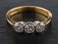 An 18ct gold, round, brilliant-cut, three-stone diamond ring,: total estimated diamond weight ca. 0.