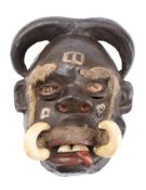 A Congolese tribal mask with painted face and tusks with applied eyebrows and moustache, 33cm high.