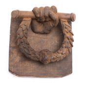 A cast iron fist and wrath door knocker with anvil: mounted on a section of oak,