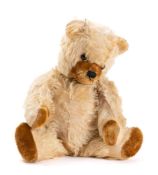 A blonde plush Teddy bear with glass eyes, stitched nose and mouth, brown plush pads and growler,