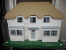 A post war child's wood doll's house with straw coloured painted pitched roof,